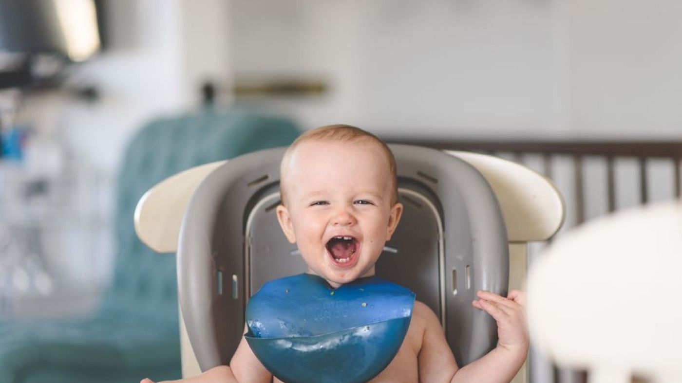 Bayi gembira makan di kerusi tinggi