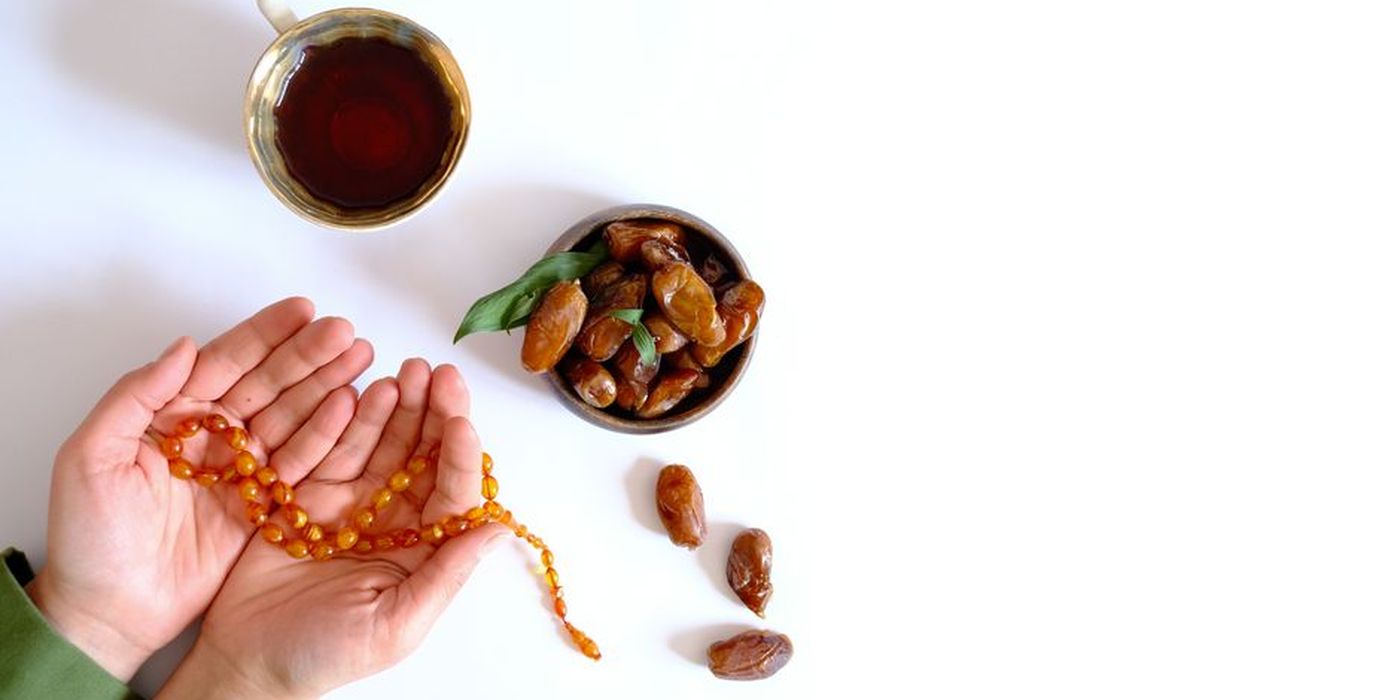 Tangan menadah doa dengan kurma dan tasbih