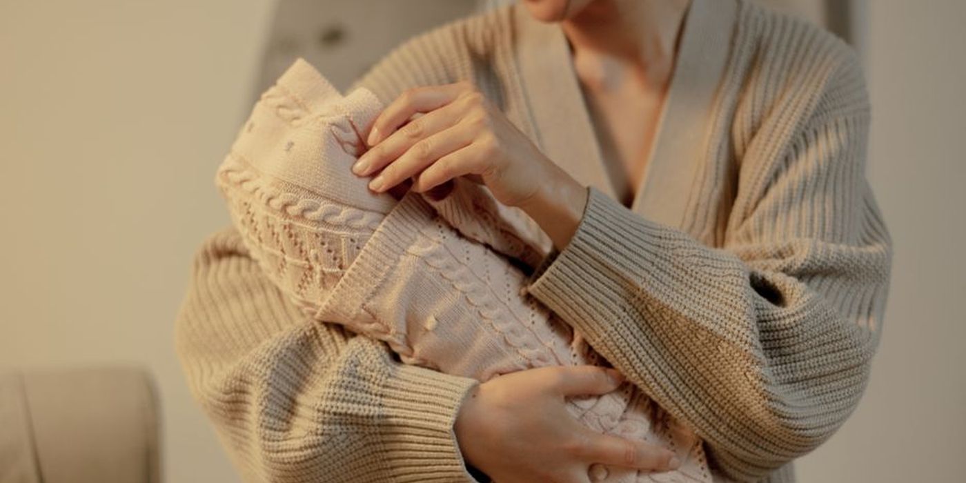 Ibu berbaju panjang mendukung bayi dalam dakapan